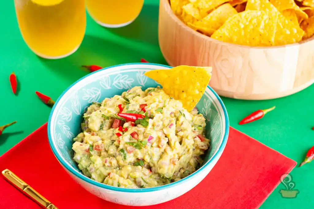 Guacamole saudável e cremosa servida em tigela com nachos ao redor