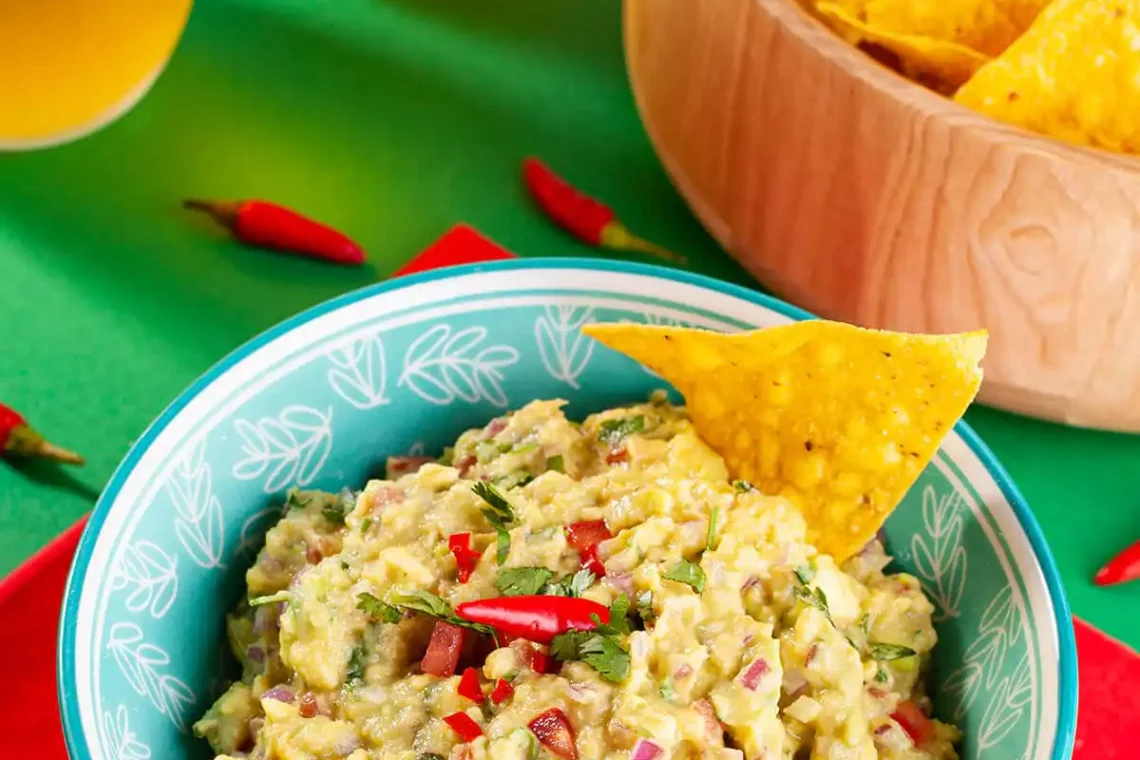 Guacamole saudável finalizado com textura cremosa e pedaços de tomate e cebola